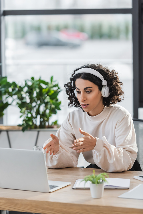 Arabian businesswoman in headphones having video call on laptop in office