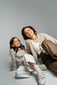 smiling girl with mother posing in fashionable autumn clothes on grey background