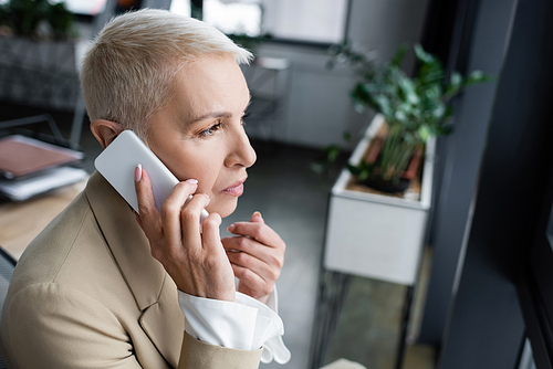 thoughtful businesswoman calling on mobile phone in blurred office
