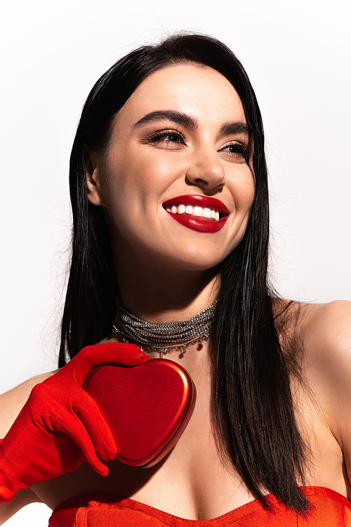Portrait of pretty brunette woman with red lips holding heart shaped gift box isolated on white