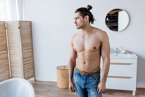 shirtless man with long hair standing in modern bathroom