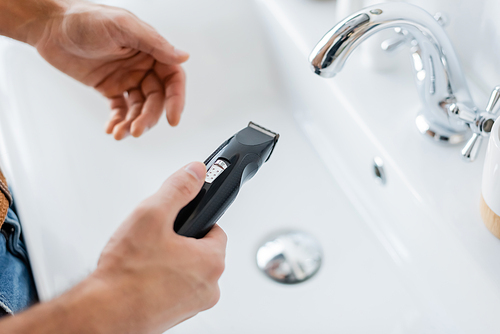 cropped view of man holding electric razor in bathroom