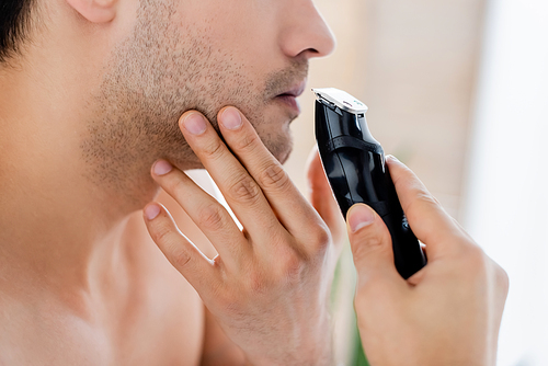 cropped view of man shaving with electric razor