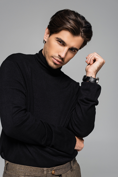 portrait of good looking man in black turtleneck posing isolated on grey