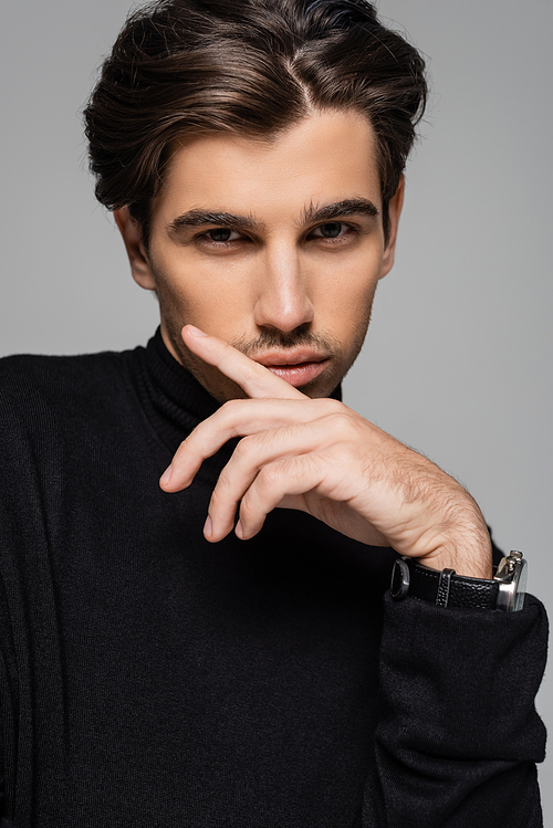 portrait of good looking model in black turtleneck looking at camera while posing isolated on grey