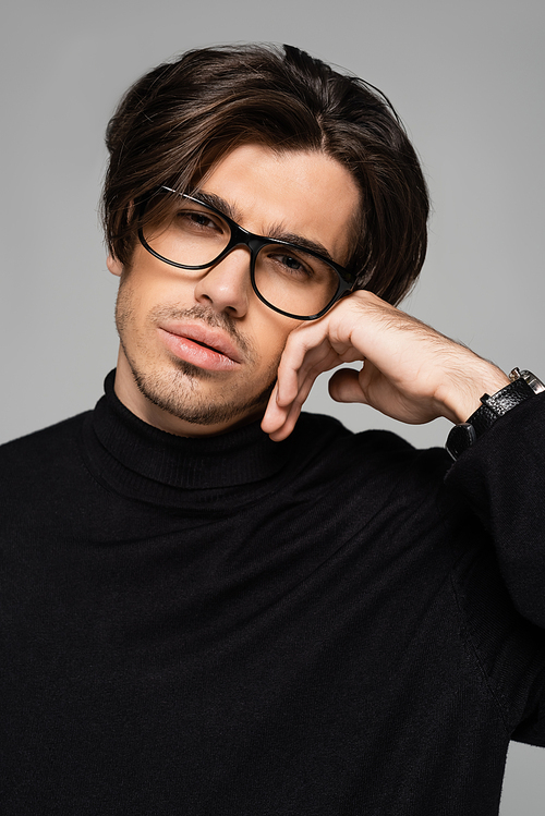 portrait of good looking man in black turtleneck and eyeglasses posing isolated on grey