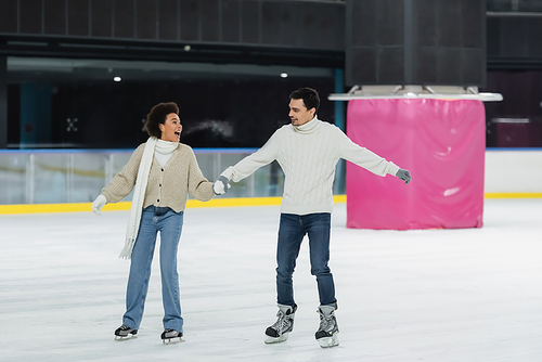 Excited african american woman ice skating with boyfriend on rink