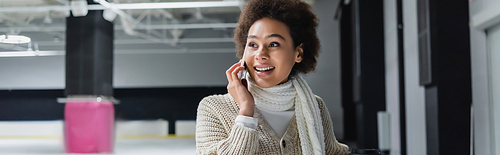 African american woman in warm clothes talking on smartphone on ice rink, banner