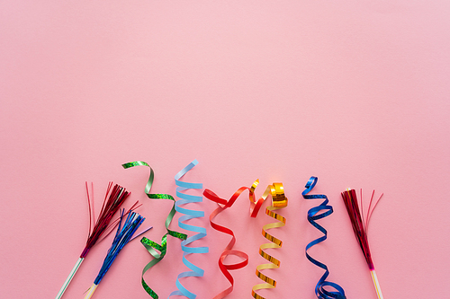 Top view of serpentine and drinking straws with tinsel on pink background
