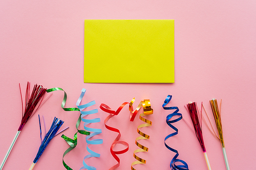 Top view of empty greeting card near drinking straws with tinsel and serpentine on pink background