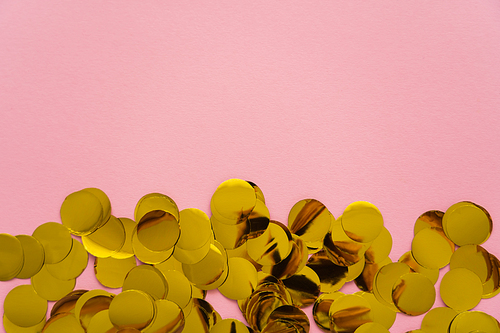 Top view of golden confetti on pink background with copy space