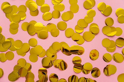 Top view of golden confetti on pink background