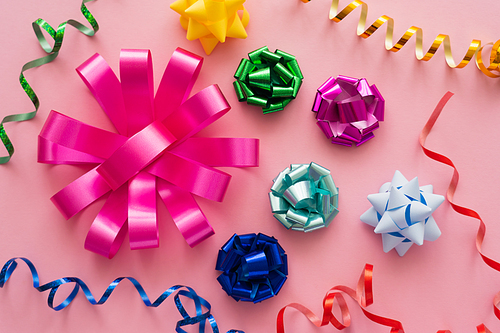 Top view of colorful gift bows and serpentine on pink background