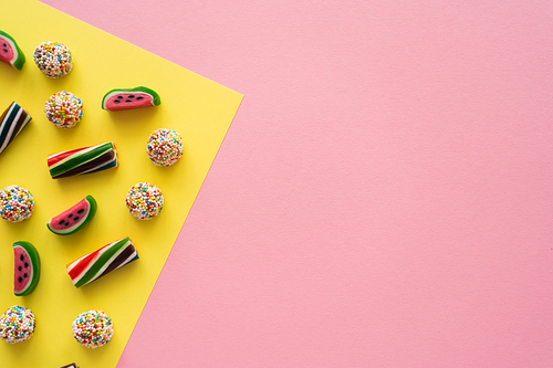 Top view of tasty candies on yellow and pink background