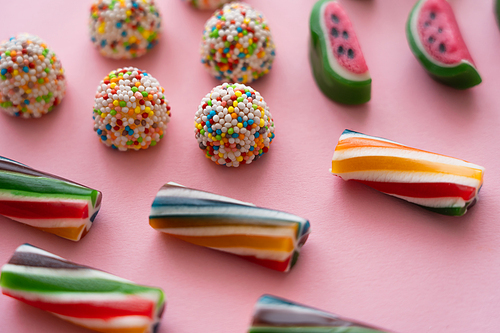 Close up view of different candies on pink background