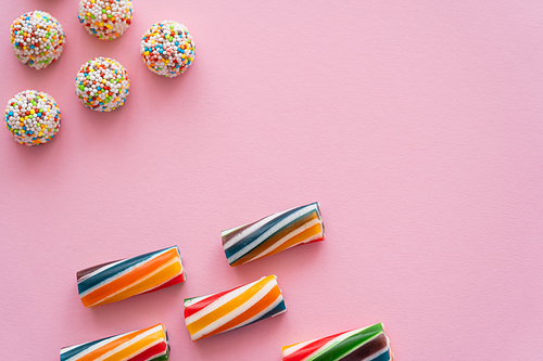 Flat lay with striped and colorful candies on pink background
