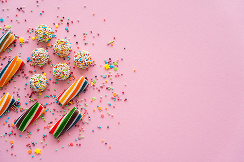 Top view of different colorful sweets and sprinkles on pink background with copy space