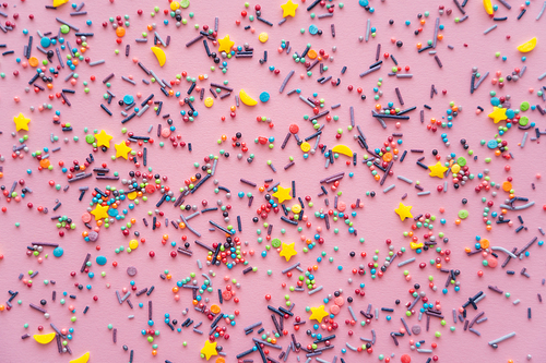 Top view of colorful sprinkles on pink background