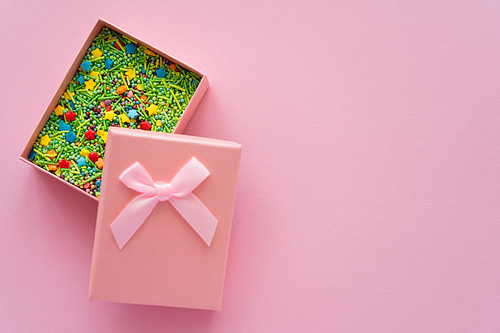 Top view of sprinkles in gift box on pink background