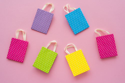 Top view of small colorful shopping bags on pink background