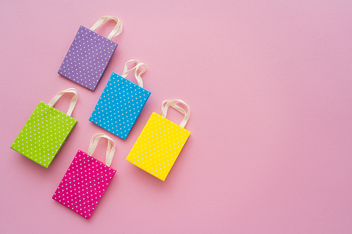 Top view of small dotted shopping bags on pink background with copy space