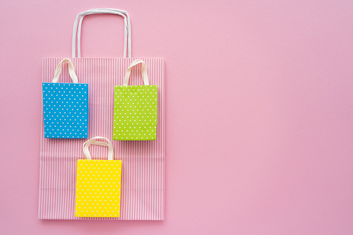 Top view of different shopping bags on pink background