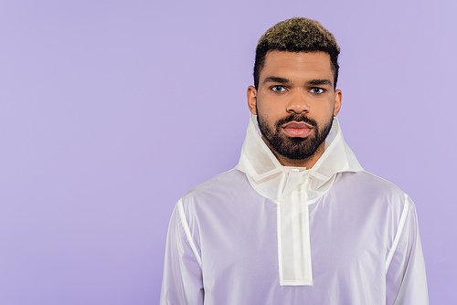 young african american man in trendy sportswear looking at camera isolated on purple