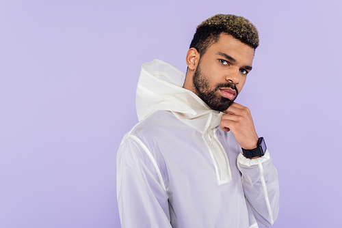 african american sportsman in stylish sportswear looking at camera isolated on purple