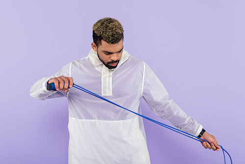 young african american sportsman exercising with skipping rope isolated on purple