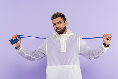 bearded african american sportsman holding skipping rope isolated on purple