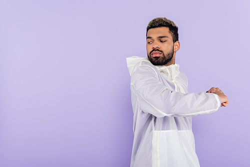 bearded african american sportsman in sportswear warming up isolated on purple