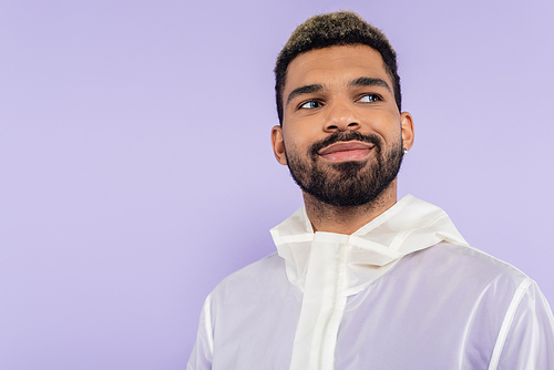 happy and bearded african american man looking away isolated on purple