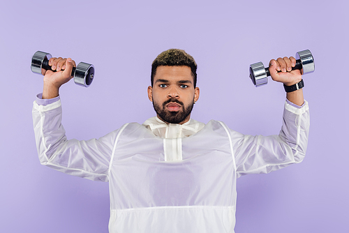 young african american man exercising with dumbbells isolated on purple