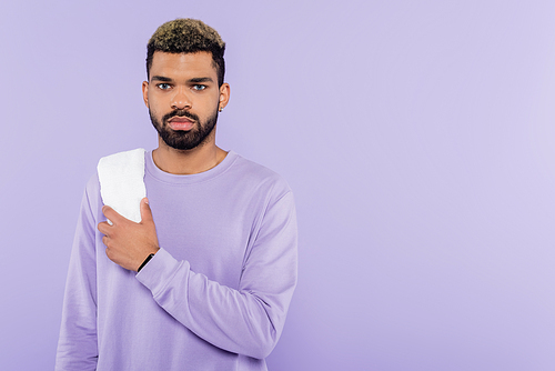 bearded african american man in sweater holding white towel isolated on purple