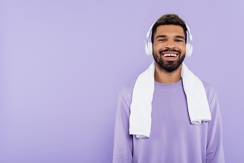 bearded and happy african american man in wireless headphones isolated on purple