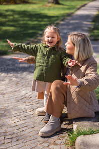 excited mother and daughter with outstretched hands having fun in park
