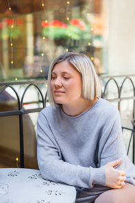 pensive and smiling woman sitting at table in street cafe