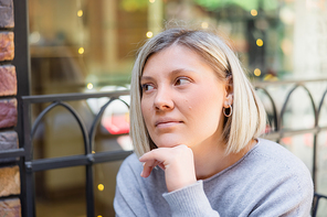 dreamy woman holding hand near chin and looking away outdoors