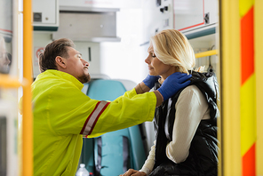 Side view of paramedic in latex gloves checking middle aged patient with hypertension in emergency vehicle