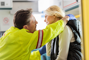 Side view of paramedic checking neck of mature patient in emergency car