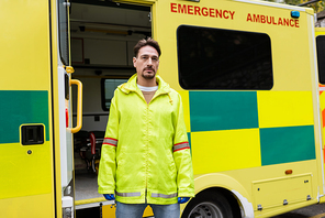 Paramedic in latex gloves standing near ambulance car outdoors