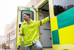 Paramedic in jacket standing near door of ambulance vehicle outdoors