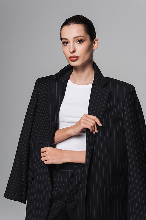Portrait of stylish brunette model wearing jacket isolated on grey