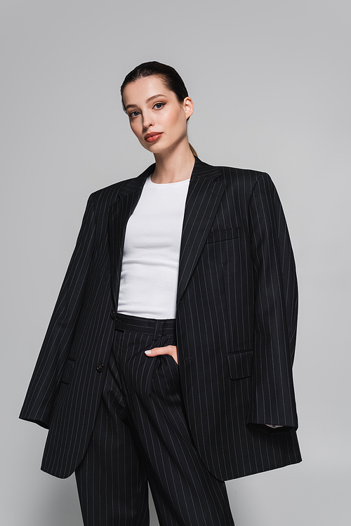 Trendy young woman in striped suit posing isolated on grey
