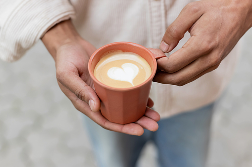 cropped view of african american man holding takeaway coffee drink with latte art in cup