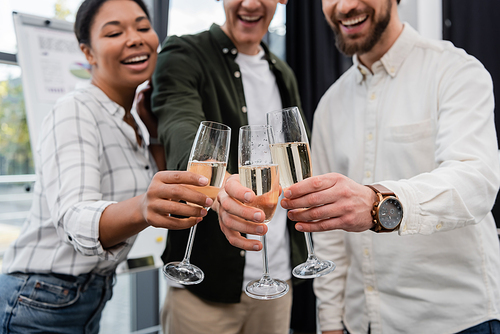 Blurred multiethnic business people clinking champagne during corporate party in office