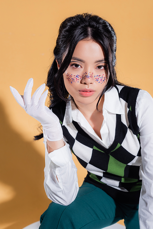 Stylish asian model with makeup posing on orange background