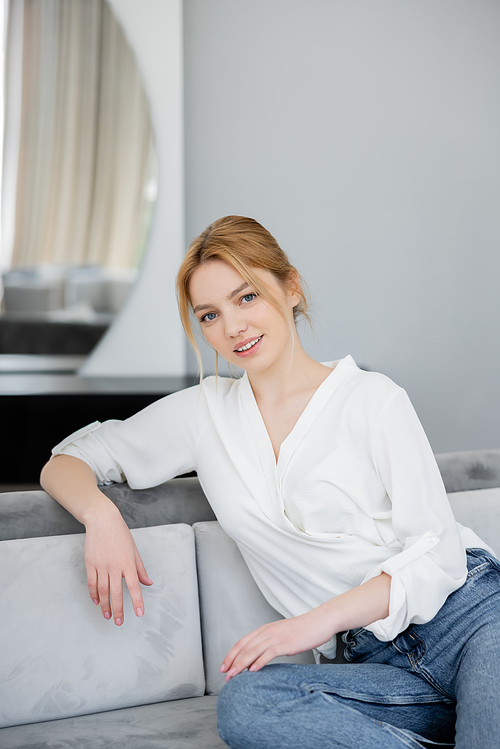 Portrait of smiling blonde woman sitting on couch