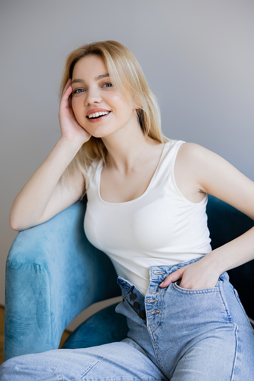 Portrait of positive young woman posing on armchair at home