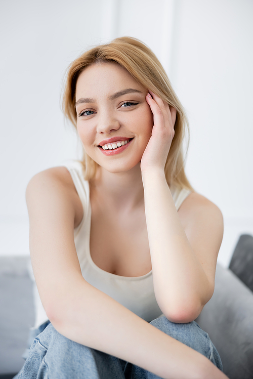Portrait of positive young woman looking at camera on blurred couch